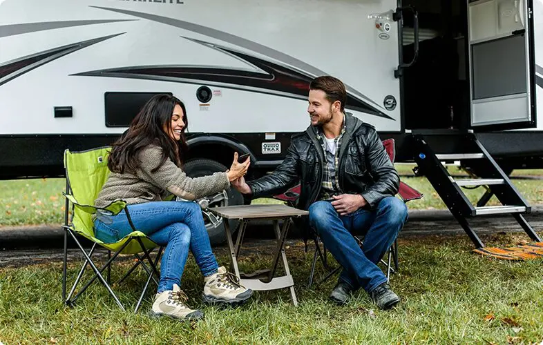6 A man and woman sitting at a table outside of an rv.