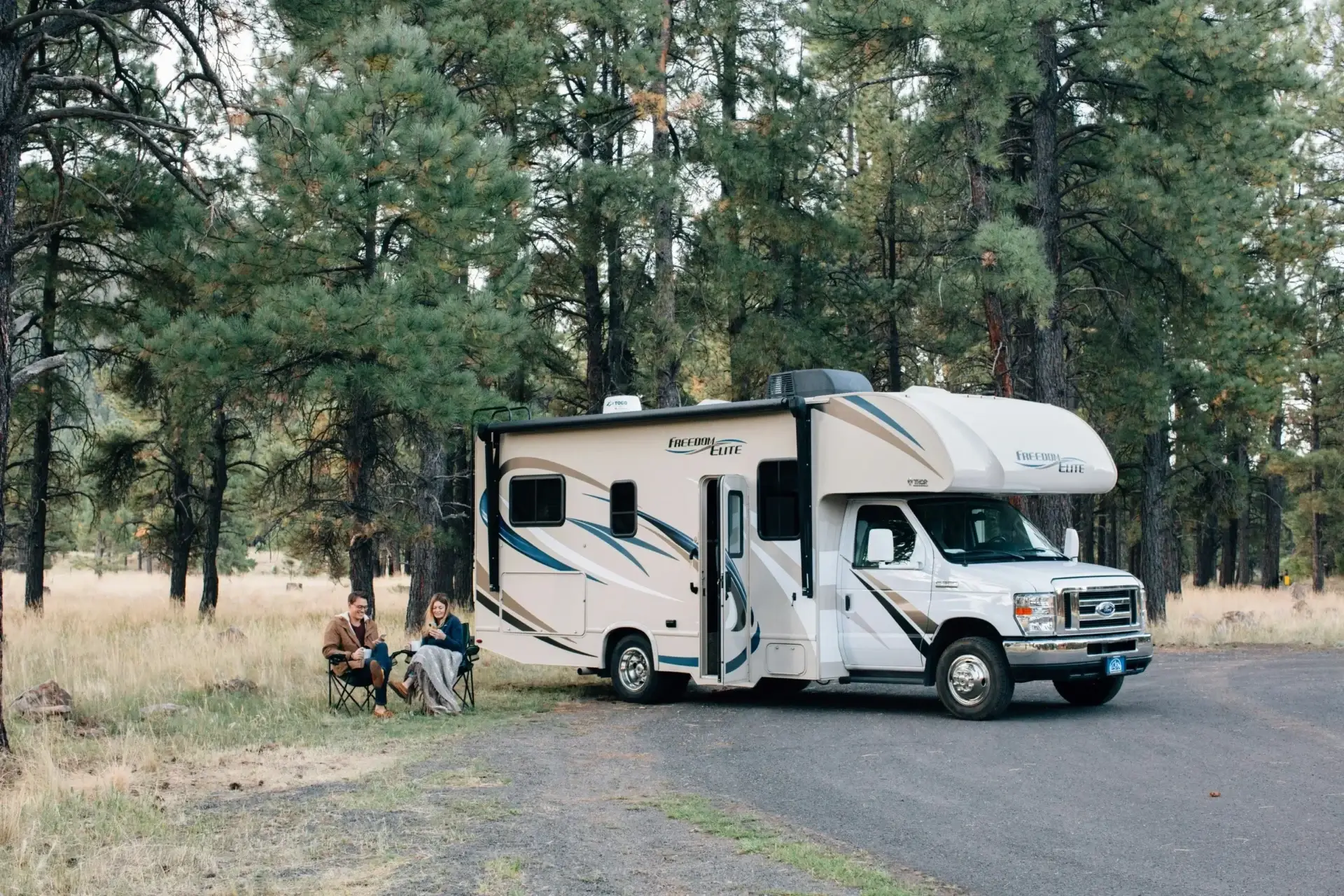 roadpass-rg-YHCIyays-unsplash-scaled (1) A white and blue rv parked on the side of a road.